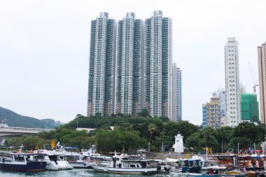 Aberdeen, Hong Kong - 16 Aralık 2024: Güneybatı Hong Kong adası kıyısı yakınında balıkçı tekneleri olan. Yüzen ünlü köyün sahil şeridi boyunca inşa edilen yüksek konut kuleleri