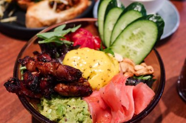 Kızarmış tavuk ve cevizli salata, turşulu zencefil, salatalık, şekerli domates, yeşil sebze, ezilmiş avokado ve şeffaf bir kasede zerdeçal tahini.