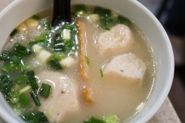 Çin usulü Hong Kong usulü taze soğanlı çorba, beyaz balık köftesi, balık dilimi ve siyah kaşık.