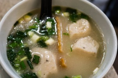 Çin usulü Hong Kong usulü taze soğanlı çorba, beyaz balık köftesi, balık dilimi ve siyah kaşık.