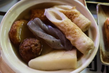 close up of Japanese hot soup Oden with hanpen, chikuwa, konnyaku, mushroom, Taikon ( radish), meatball in a white bowl clipart