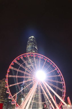 Merkez, Hong Kong - 23 Aralık 2024: Ferris Wheel Hong Kong Gözlem Çarkı ve Uluslararası Finans Merkezi (IFC) gece vakti Victoria Limanı 'nın yanındaki parlak ışıkla