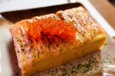 close up of rectangular Japanese rolled egg omelette (Tamagoyaki) with salmon roe (ikura) and seaweed powder clipart