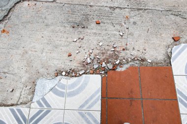 Döşeme bölümünün bir kısmını kırmızı kiremit karışımı bir ızgara deseni ve dalgalı eğimli beyaz kiremitlerle kaplayın. Kırık kiremitler ve enkaz parçaları etrafa saçılmış..