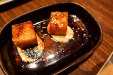 İki parça İspanyol tapasını siyah bir tabakta kızartılmış patates mili feuille ile kapatın.