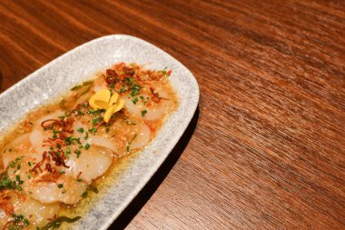 İspanyol tapas başlangıç aperatifi çiğ çiğ deniz tarağı ceviche sos ve fotokopi alanı beyaz bir tabak ve ahşap masa üzerinde