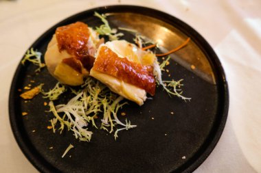 İki parça Çin tavuğunu siyah bir tabakta yakın.