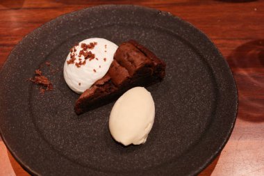 Çikolatalı kekin yanına vanilyalı dondurma ve kremalı gri bir tatlı tabağı koy. 