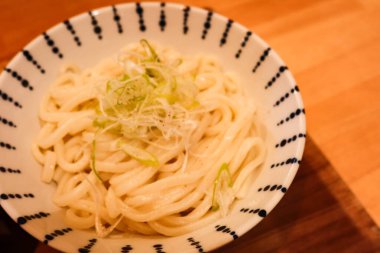 Japon kaynamış çorbası beyaz udon şehriyesini bir kase içinde, ahşap masada fotokopi alanı olan bir tabakta yakın çekim yapın.
