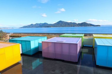 Otake, Hiroshima, Japonya - 12 Aralık 2024: SIMOSE (Simose Sanat Müzesi Simose Art Garden Villa) güzel bir hava mavi gökyüzü gününde gökkuşağı renkli kargo kutusu benzeri bir alanda sergilenmektedir.