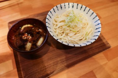 Japon miso çorbasının yanına büyük bir kase beyaz udon eriştesi ve ahşap tepside taze soğan koyun.