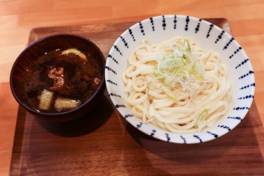 Japon miso çorbasının yanına büyük bir kase beyaz udon eriştesi ve ahşap tepside taze soğan koyun.