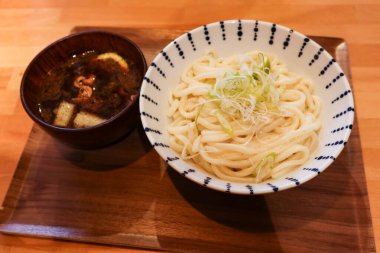 Japon miso çorbasının yanına büyük bir kase beyaz udon eriştesi ve ahşap tepside taze soğan koyun.