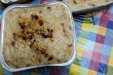 close up of steamed homemade Chinese Lunar New Year traditional food radish turnip cake pudding (Lo Pak Go or Luo Bo Gao) in aluminium foil tray with colourful table cloth clipart