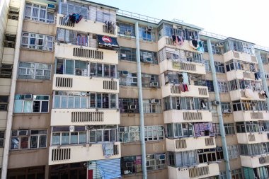 Fuk Loi Malikanesi, Tsuen Wan, Hong Kong - 4 Ocak 2025: Pencereli ve asılmış elbiseli eski bir apartman dairesi. Gündüz vakti dış bina inşa ediliyor
