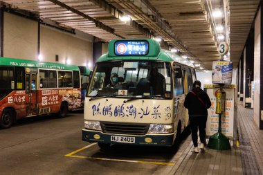 Merkez, Hong Kong - 11 Ocak 2025: Yeşil Mini-otobüs gündüz yolda Çince sözcüklerle dolu durak kapalı toplu taşıma otobüs durağı. Bir yolcu biniyor.
