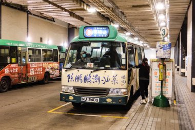 Merkez, Hong Kong - 11 Ocak 2025: Yeşil Mini-otobüs gündüz yolda Çince sözcüklerle dolu durak kapalı toplu taşıma otobüs durağı. Bir yolcu biniyor.