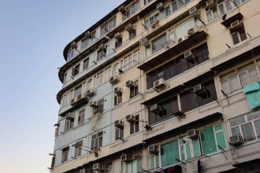 Kowloon City, Hong Kong - 14 Ocak 2025: kopyalanmış eski bir apartmanın dış tarafı. Asistanlar dışarıda kıyafet asıyor.