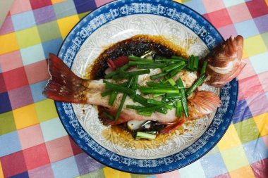 close up of Hong Kong style Chinese homemade steamed groupers fish with spring onion and soy sauce on a plate clipart