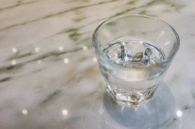 Mermer bir masanın üzerindeki saydam su bardağını kapat.