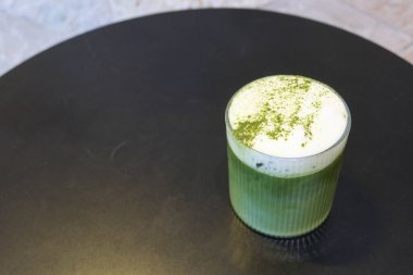 Soğuk buzlu sütlü yeşil çay sütlü sütlü sütlü sütlü sütlü sütlü sütlü sütlü sütlü sütlü sütlü sütlü sütlü sütlü sütlü sütlü sütlü sütlü sütlü sütlü sütlü sütlü sütlü sütlü sütlü sütlü sütlü kahve tozu siyah bir masada şeffaf bir bardakta.