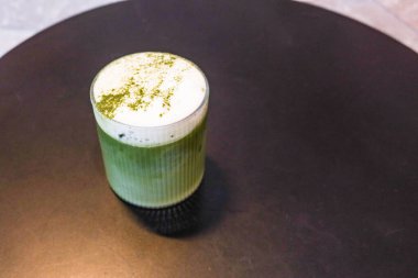 Soğuk buzlu sütlü yeşil çay sütlü sütlü sütlü sütlü sütlü sütlü sütlü sütlü sütlü sütlü sütlü sütlü sütlü sütlü sütlü sütlü sütlü sütlü sütlü sütlü sütlü sütlü sütlü sütlü sütlü sütlü sütlü kahve tozu siyah bir masada şeffaf bir bardakta.