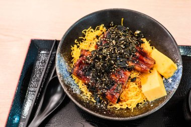 Japon yumurtalı böreğini ve ızgara yılan balığı pirincini siyah tepside çubuklarla Unadon 'a yakın tut.