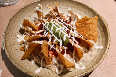 Meksika atıştırmalıkları. Ekşi kremalı ve avokado soslu. Yuvarlak tabakta.