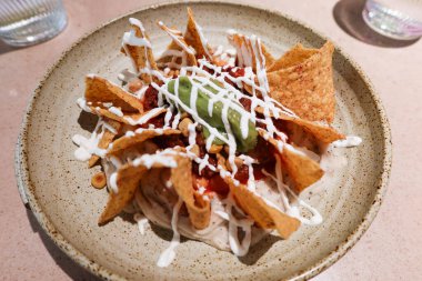 Meksika atıştırmalıkları. Ekşi kremalı ve avokado soslu. Yuvarlak tabakta.