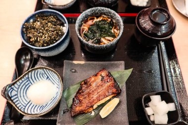 Izgara balık, onsen yumurtası, miso çorbası, deniz yosunlu miso çorbası ve susamlı pilav ve deniz yosunuyla kaplanmış bir Japon sofrası.