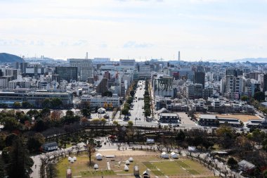 Himeji, Japonya - 12 Aralık 2024: Büyük parkı ve uzun yolu olan şehir manzarası. Himeji Kalesi 'nden gündüz gözüyle iki taraf boyunca binalar
