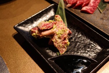 Wasabi çiğ wagyu et parçalarını siyah bir tabakta ızgara yakiniku yapmaya hazır hale getir.
