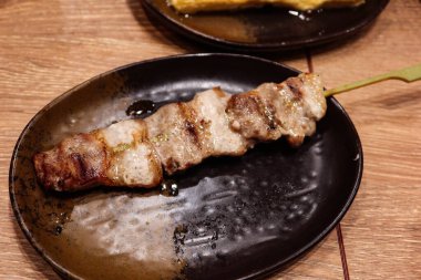 Japon Yakitori domuz şiş yakın bir tabakta bambu çubuk ile