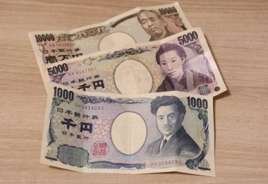 10 bin yen, 5 bin yen ve 1 bin yen 'lik banknot paralarını ahşap bir masaya yatırın.