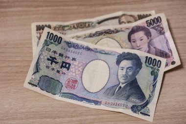 10 bin yen, 5 bin yen ve 1 bin yen 'lik banknot paralarını ahşap bir masaya yatırın.