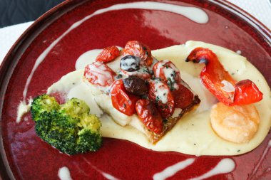 Izgara deniz levreğini deniz tarağıyla kapat. Brokoli ve patates püresi kırmızı tabakta.