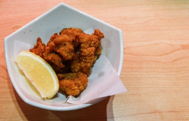 Kızarmış tavuk parçalarını polis alanına sahip beyaz bir tabakta limon dilimiyle kapat.