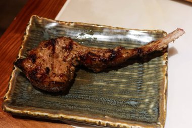 Izgara kuzu eti, koyun budu askısı ve yeşil bir tabakta fotokopi alanı.