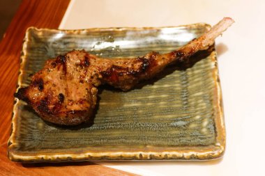 Izgara kuzu eti, koyun budu askısı ve yeşil bir tabakta fotokopi alanı.