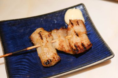 Tayland usulü ızgara domuz budu, yanında salata sosu ve mavi tabak.