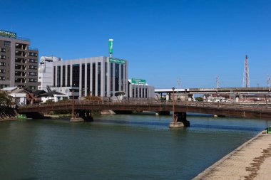 Kokura, Kitakyushu, Japonya - 3 Kasım 2024: Mavi gökyüzünde binaları olan Tokiwa Köprüsü Murasaki Nehri boyunca güzel hava koşulları