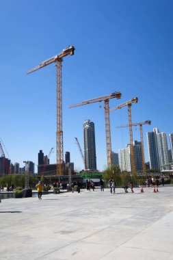 Kai Tak, Hong Kong... 12 Ocak 2025: İnşaat çalışmaları devam ediyor. Ön planda yürüyen çember açık alanda ve arkada modern gökdelenler var..