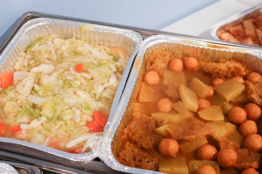 İki Çin yemeği, satay körili balık köftesi şalgam ve domuz derisi ve alüminyum folyoda kızartılmış lahana ve havuç tabağı.