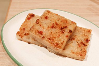 Çin Dim Sum 'una yakın beyaz bir tabakta üç parça şalgam keki (Çin Lo Pak Go)