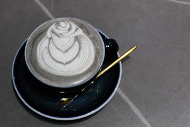 Gri arkaplanlı ve fotokopi alanı olan kahve resimli, sıcak, siyah susamlı latteyi kapat.