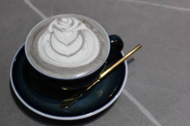 Gri arkaplanlı ve fotokopi alanı olan kahve resimli, sıcak, siyah susamlı latteyi kapat.