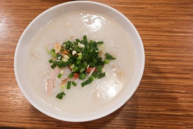 Kaynamış Çin lapası, taze soğan ve yer fıstığı ve fotokopi alanı olan ahşap bir masa.