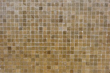 Küçük kare mozaik fayanslardan oluşmuş desenli bir duvarın yakın görüntüsü. Fayanslar, ağırlıklı olarak kahverengi ve bej tonlarında bir dizi sıcak toprak tonu içerir ve arka plan olarak kullanılabilir.