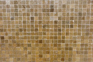 Küçük kare mozaik fayanslardan oluşmuş desenli bir duvarın yakın görüntüsü. Fayanslar, ağırlıklı olarak kahverengi ve bej tonlarında bir dizi sıcak toprak tonu içerir ve arka plan olarak kullanılabilir.