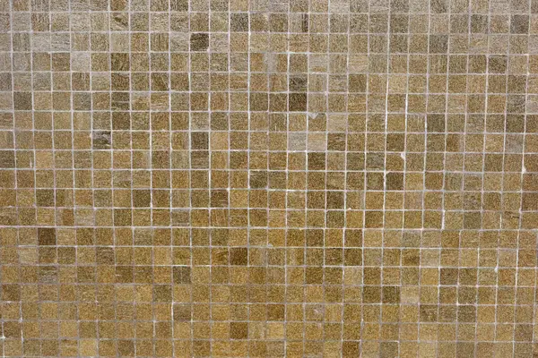 Küçük kare mozaik fayanslardan oluşmuş desenli bir duvarın yakın görüntüsü. Fayanslar, ağırlıklı olarak kahverengi ve bej tonlarında bir dizi sıcak toprak tonu içerir ve arka plan olarak kullanılabilir.